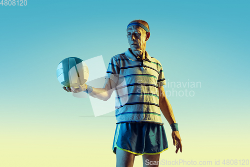 Image of Senior man playing volleyball in sportwear on gradient background and neon light