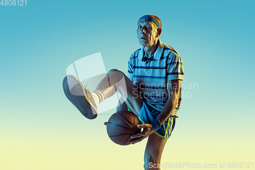 Image of Senior man playing basketball in sportwear on gradient background and neon light