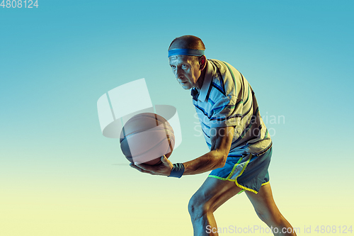 Image of Senior man playing basketball in sportwear on gradient background and neon light