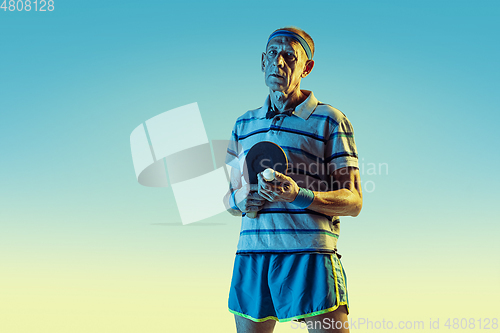 Image of Senior man playing table tennis in sportwear on gradient background and neon light