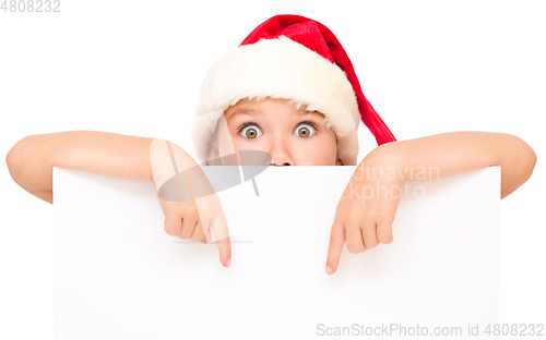 Image of Little girl in santa hat is holding blank board