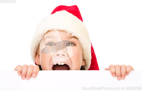 Image of Little girl in santa hat is holding blank board