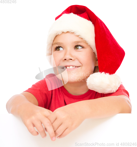 Image of Little girl in santa hat is holding blank board