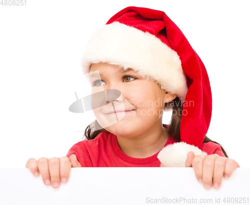 Image of Little girl in santa hat is holding blank board