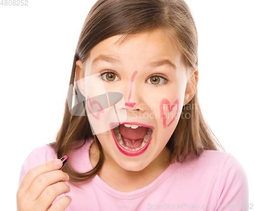 Image of Little girl is applying lipstick on her cheek