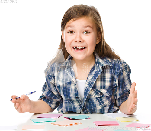 Image of Girl is writing on color stickers using pen