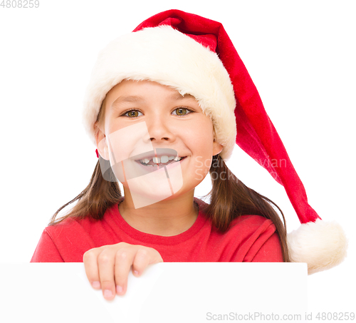 Image of Little girl in santa hat is holding blank board