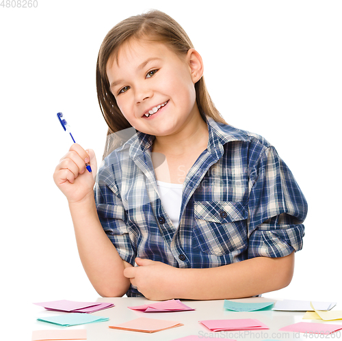 Image of Girl is writing on color stickers using pen