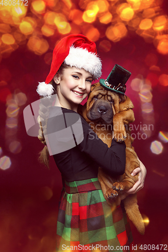 Image of Pretty girl in christmas hat with shar pei puppy