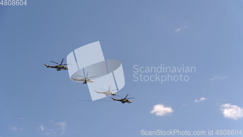 Image of Combat helicopters Mi-24 fly in blue sky