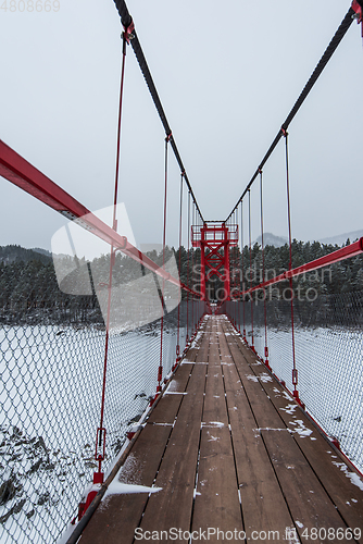 Image of Suspension hanging bridge above winter frozen river