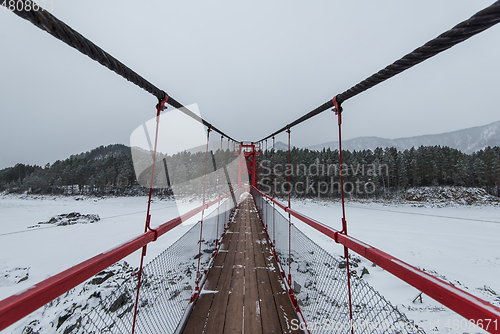 Image of Suspension hanging bridge above winter frozen river