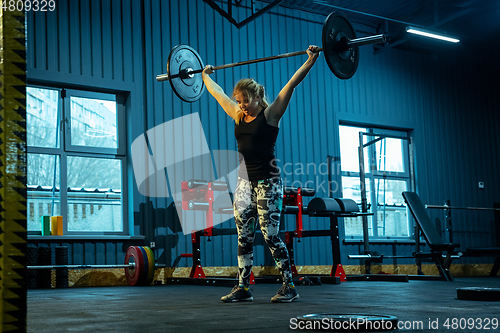 Image of Caucasian teenage girl practicing in weightlifting in gym