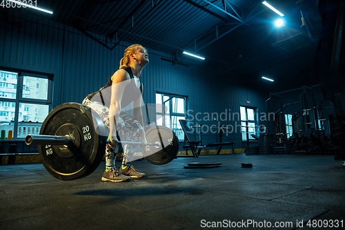 Image of Caucasian teenage girl practicing in weightlifting in gym