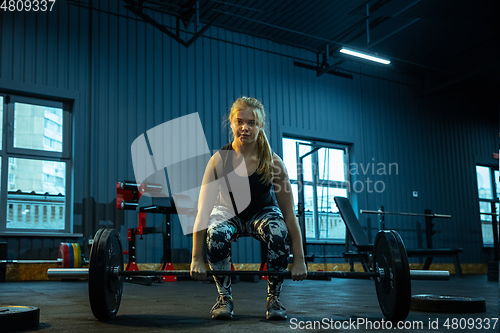 Image of Caucasian teenage girl practicing in weightlifting in gym