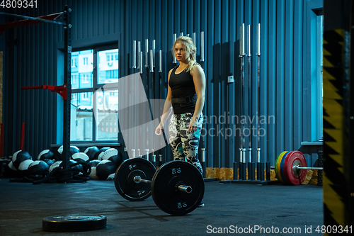 Image of Caucasian teenage girl practicing in weightlifting in gym