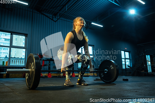 Image of Caucasian teenage girl practicing in weightlifting in gym