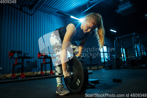 Image of Caucasian teenage girl practicing in weightlifting in gym