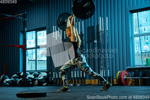 Image of Caucasian teenage girl practicing in weightlifting in gym