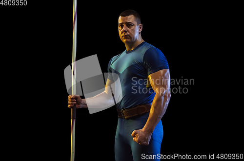 Image of Male athlete practicing in throwing javelin isolated on black studio background in neon light