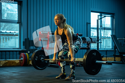 Image of Caucasian teenage girl practicing in weightlifting in gym