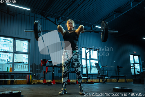 Image of Caucasian teenage girl practicing in weightlifting in gym