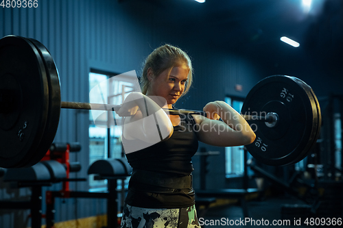 Image of Caucasian teenage girl practicing in weightlifting in gym