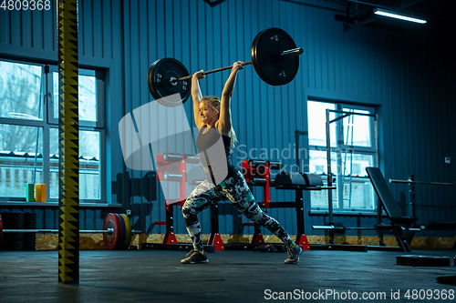 Image of Caucasian teenage girl practicing in weightlifting in gym