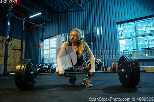 Image of Caucasian teenage girl practicing in weightlifting in gym