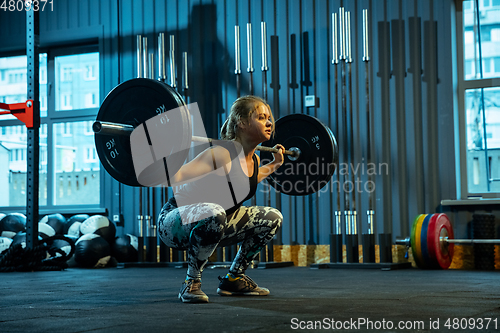 Image of Caucasian teenage girl practicing in weightlifting in gym