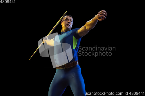 Image of Male athlete practicing in throwing javelin isolated on black studio background in neon light