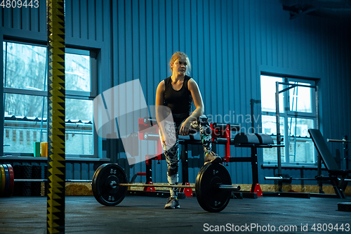 Image of Caucasian teenage girl practicing in weightlifting in gym