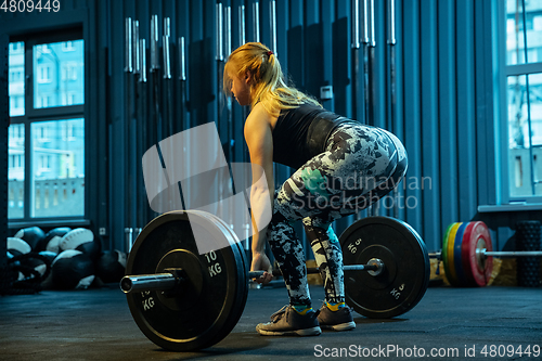 Image of Caucasian teenage girl practicing in weightlifting in gym