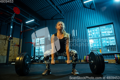 Image of Caucasian teenage girl practicing in weightlifting in gym