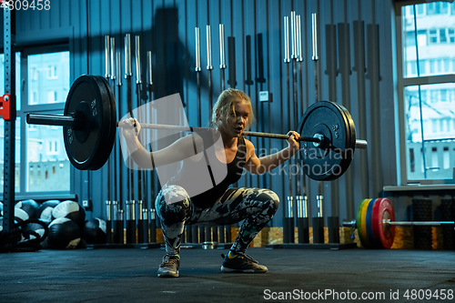 Image of Caucasian teenage girl practicing in weightlifting in gym