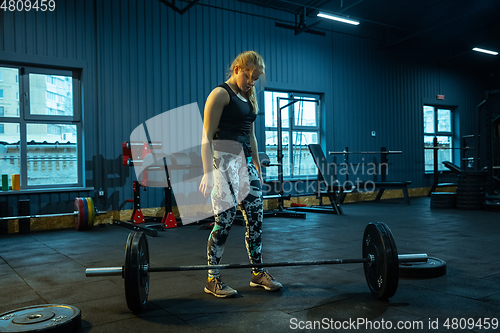 Image of Caucasian teenage girl practicing in weightlifting in gym