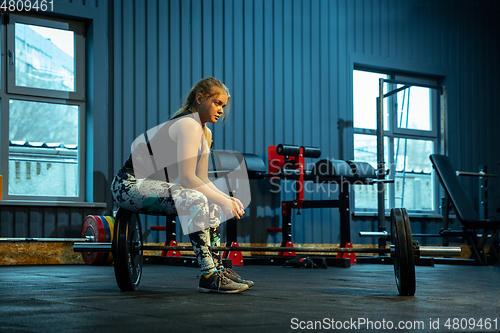 Image of Caucasian teenage girl practicing in weightlifting in gym