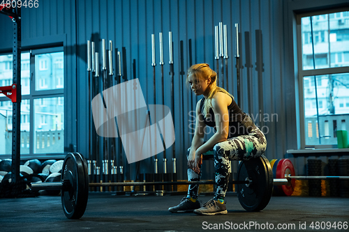 Image of Caucasian teenage girl practicing in weightlifting in gym