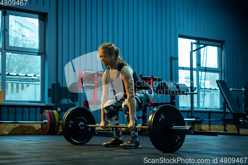 Image of Caucasian teenage girl practicing in weightlifting in gym