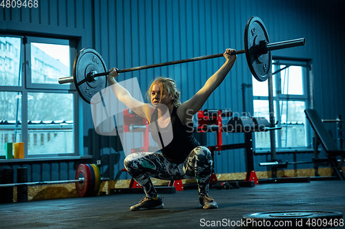 Image of Caucasian teenage girl practicing in weightlifting in gym