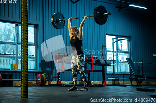 Image of Caucasian teenage girl practicing in weightlifting in gym