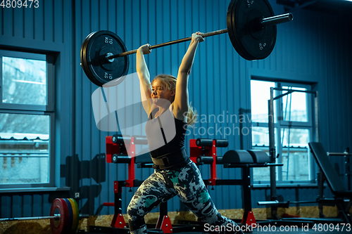 Image of Caucasian teenage girl practicing in weightlifting in gym