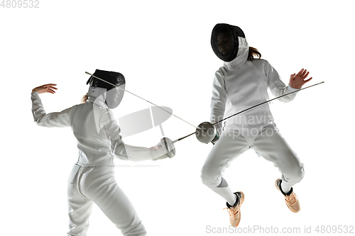 Image of Teen girls in fencing costumes with swords in hands isolated on white background