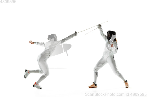 Image of Teen girls in fencing costumes with swords in hands isolated on white background