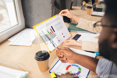 Image of Colleagues working together in modern office using devices and gadgets during negotiations