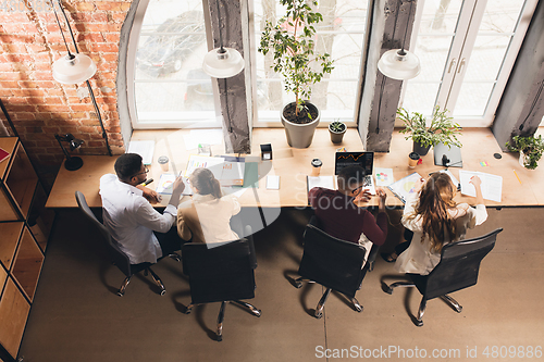 Image of Colleagues working together in modern office using devices and gadgets during negotiations. Top view.