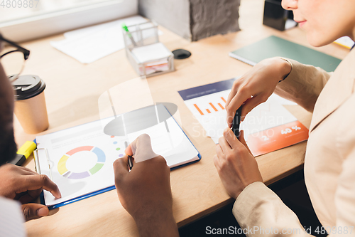 Image of Colleagues working together in modern office using devices and gadgets during negotiations