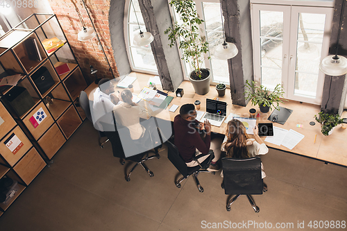 Image of Colleagues working together in modern office using devices and gadgets during negotiations. Top view.