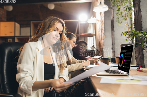 Image of Colleagues working together in modern office using devices and gadgets during negotiations