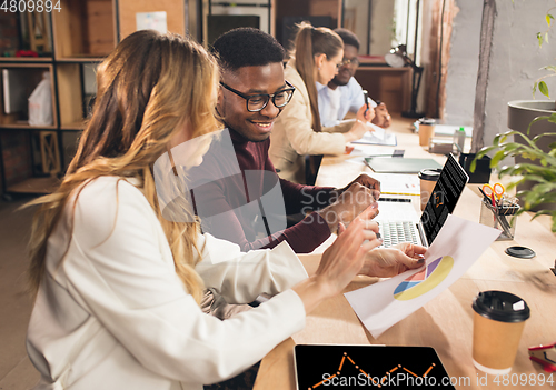 Image of Colleagues working together in modern office using devices and gadgets during negotiations